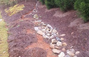 damaged dry creek bed before repair by Pannone’s Lawn Pros & Landscaping