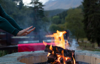man warming his hands by the fire in a fire pit at dusk